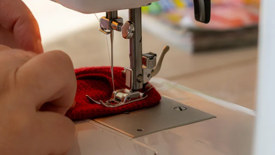 Hands guiding fabric under sewing machine.