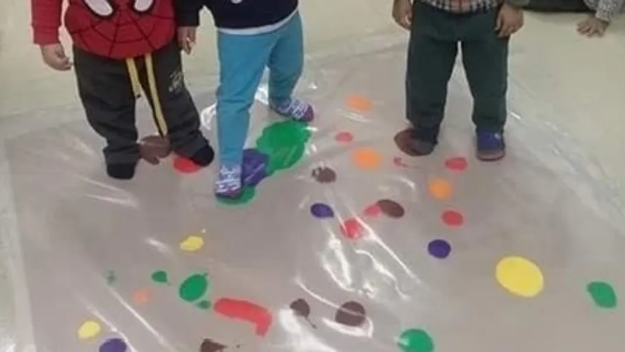 Drei Kinder stehen auf plastikgefüllter Farbe.