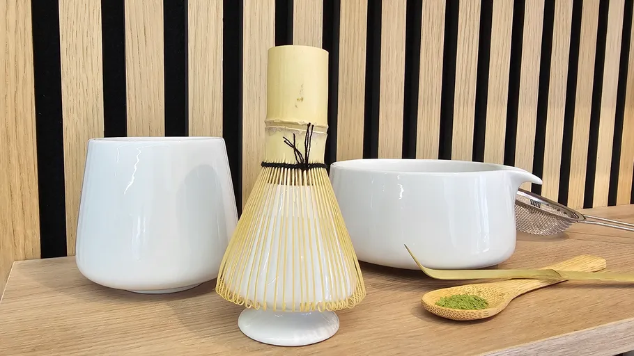 Matcha-Set mit Besen und Schalen auf Holzregal.
