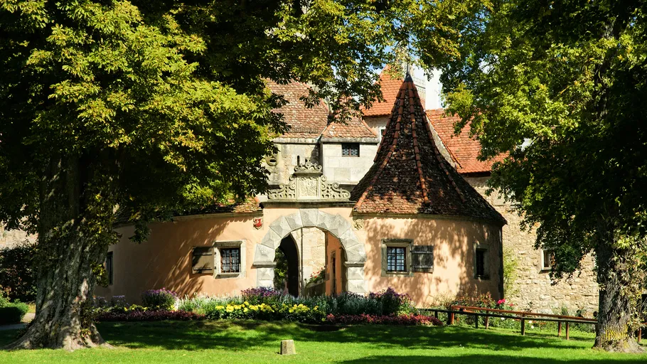 Historic building with tower, surrounded by trees.