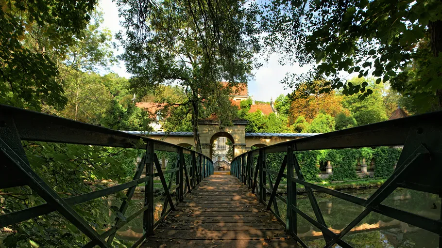 Holzbrücke führt zu einem Parkgebäude.