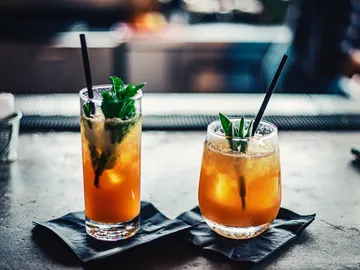 Two cocktails are on dark napkins.