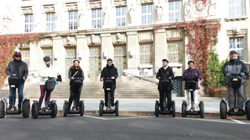 Personen fahren Segways vor historischem Gebäude.