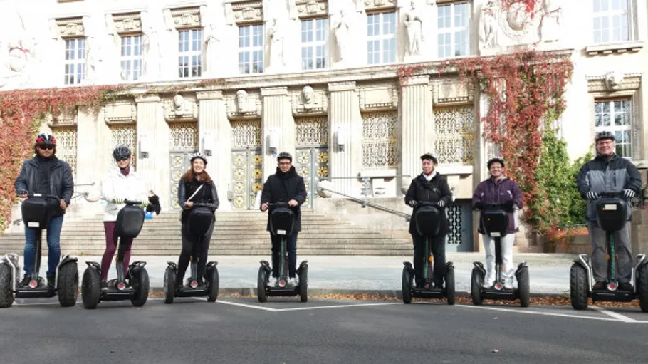 People riding segways outside historic building.