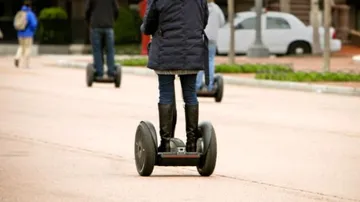 People riding Segways on a city street.