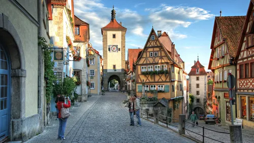 Tourists photographing medieval street with tower.