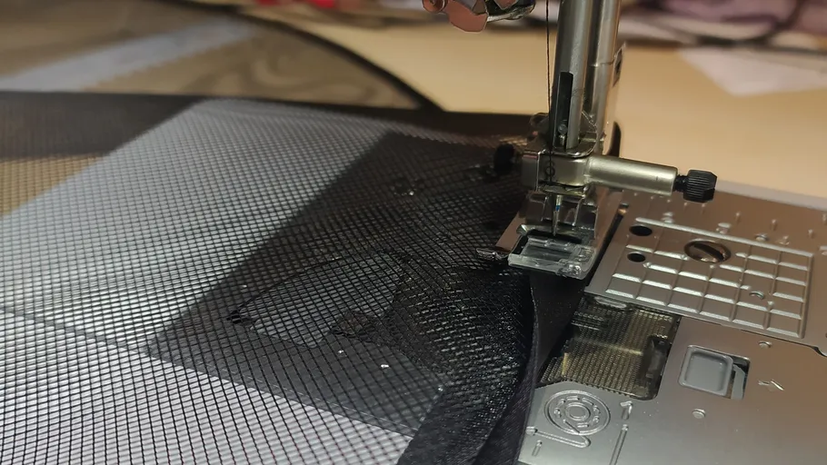 Nähmaschine näht schwarzen Netzstoff.