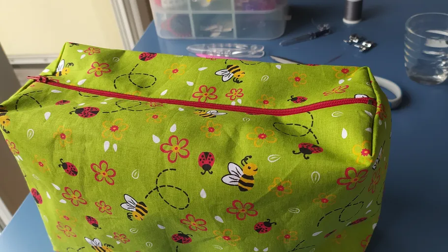 Grünes Etui mit Bienen und Marienkäfern auf Tisch.