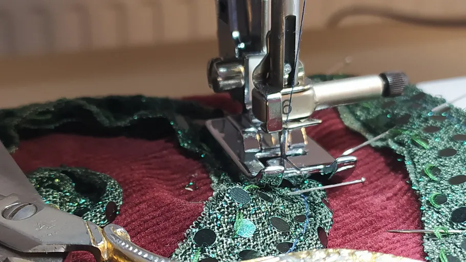 Nähmaschine näht grünen Stoff auf weinrot.
