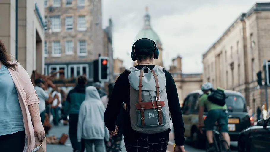 Person walking in city street, wearing headphones.