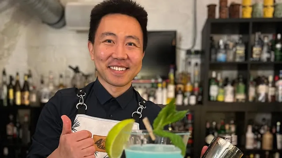 Smiling bartender gives thumbs up in bar.