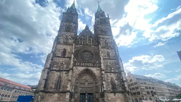 Gothic cathedral with twin towers under cloudy sky.