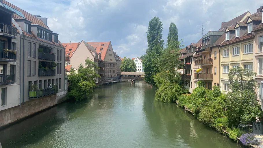 Fluss fließt zwischen Wohngebäuden und Grünflächen.