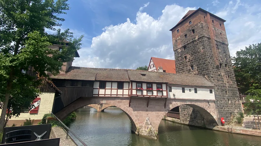 Historic bridge with house and tower over river.