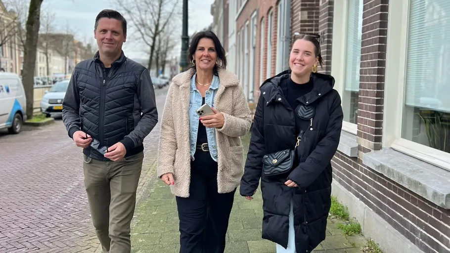 Three people walking on a city sidewalk.