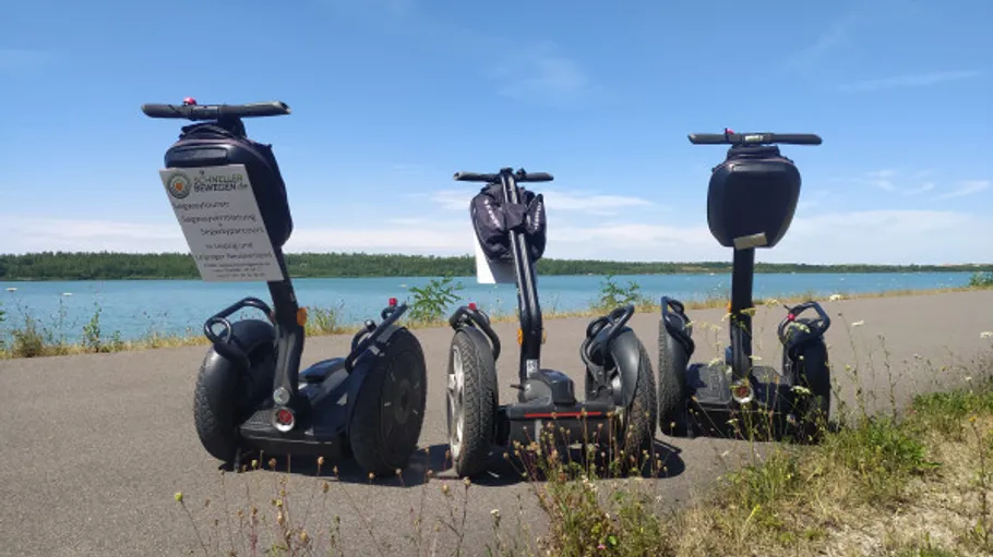 Three Segways parked by a lakeside path.
