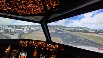 Airplane cockpit approaching runway in daylight.