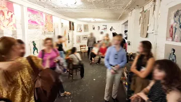People socializing at art gallery exhibition.