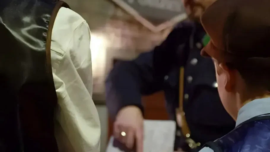 People in historical clothing talking inside building.