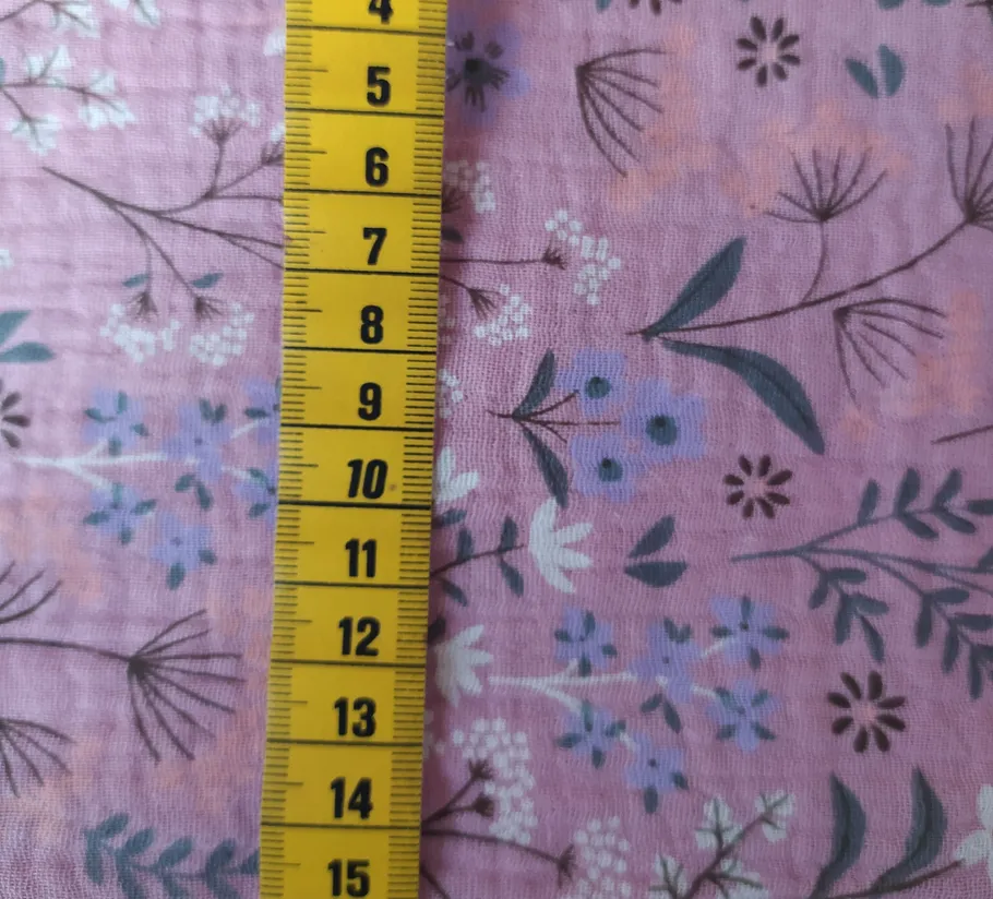 Yellow measuring tape on floral pink fabric.