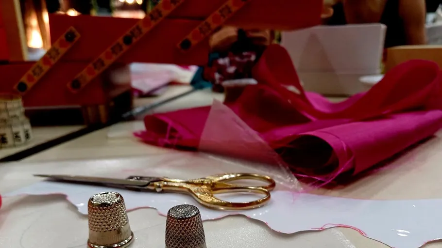 Nähwerkzeuge und pinker Stoff auf Tisch.