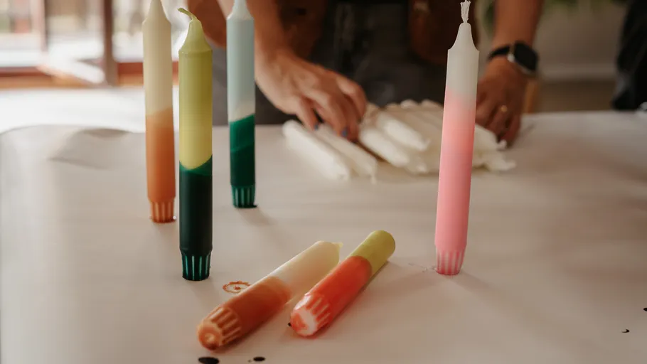 Colorful candles on table, person arranging them.