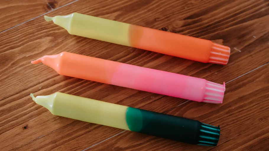Drei bunte Kerzen auf Holztisch.