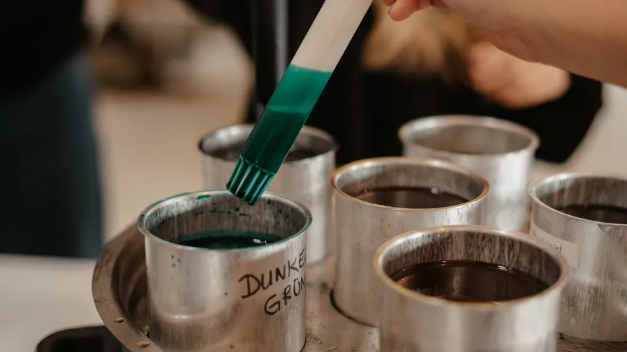 Hand holding brush over colorful dye cups.