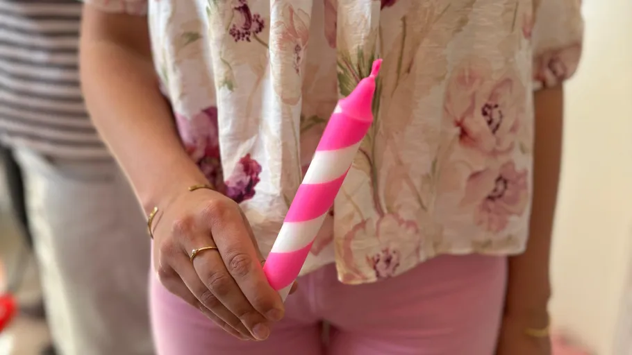 Person hält pink-weiß gestreifte Kerze.