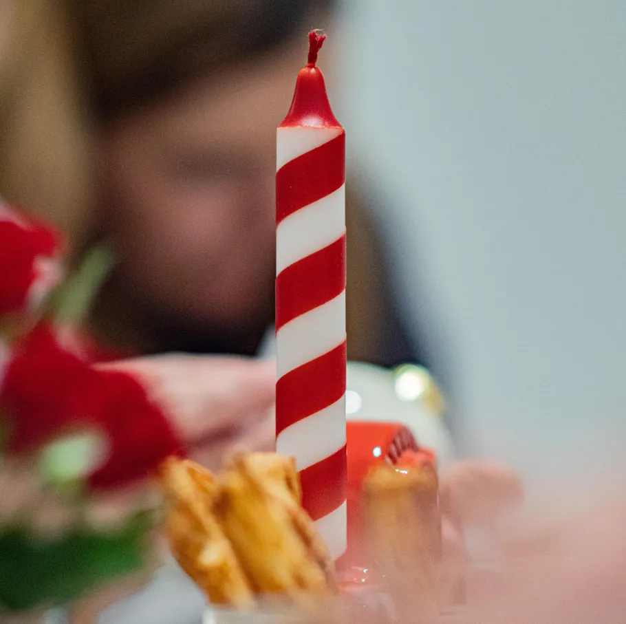 Striped candle in a blurred indoor setting.