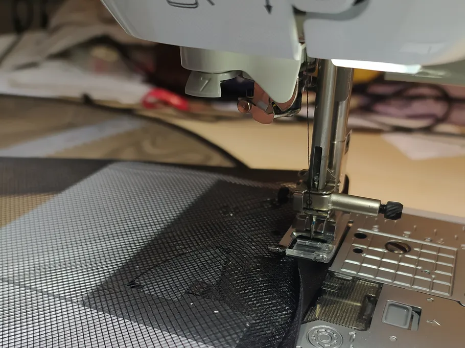 Nähmaschine näht schwarzen Netzstoff.