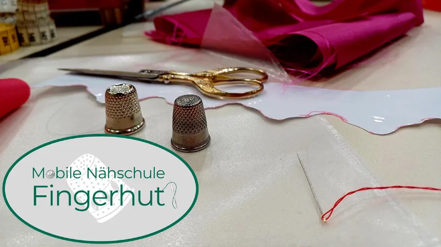 Nähwerkzeuge und Stoff auf einem Tisch.