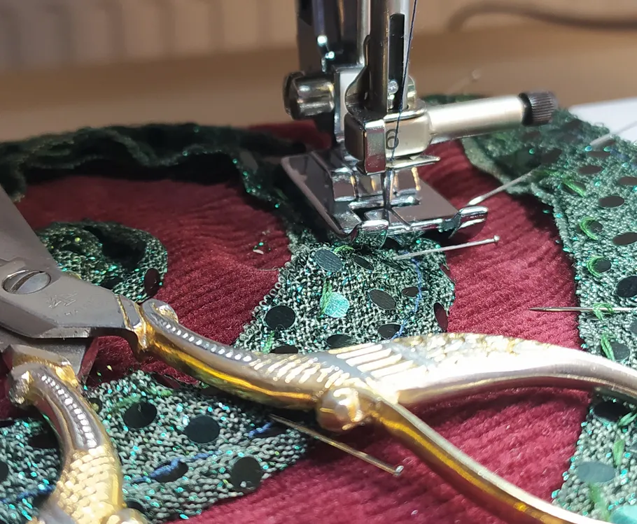 Sewing machine stitching green lace fabric.