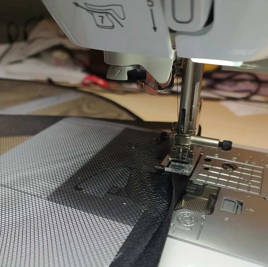 Nähmaschine näht schwarzen Netzstoff.