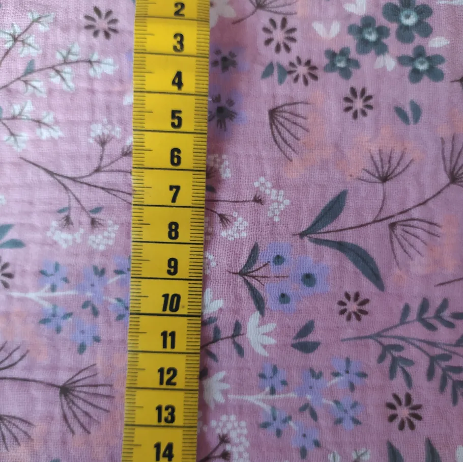 Yellow tape measure on floral pink fabric.