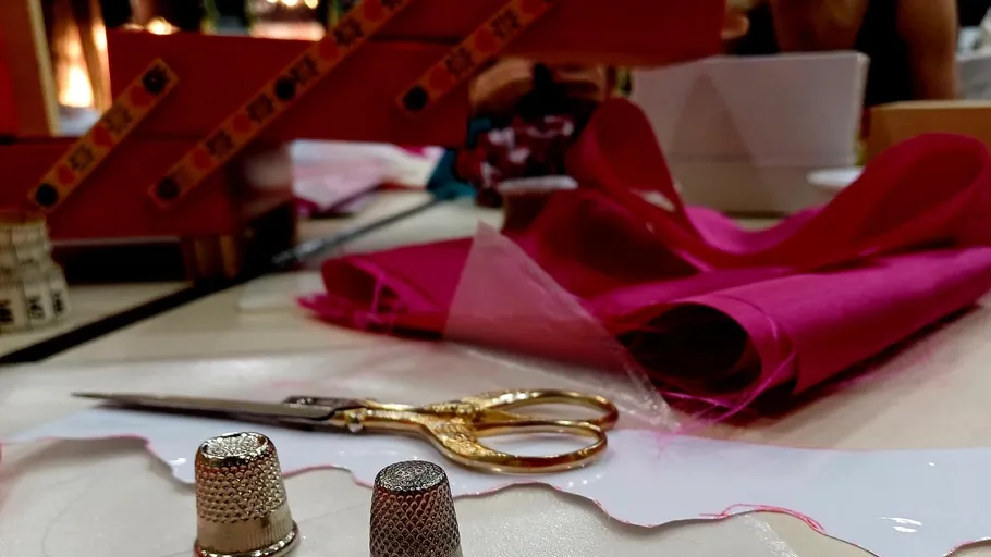 Sewing thimbles, scissors, fabric on a table.