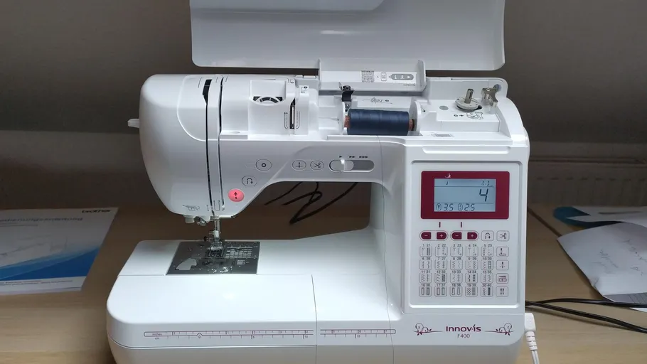 Nähmaschine auf Tisch, digitales Display aktiv.