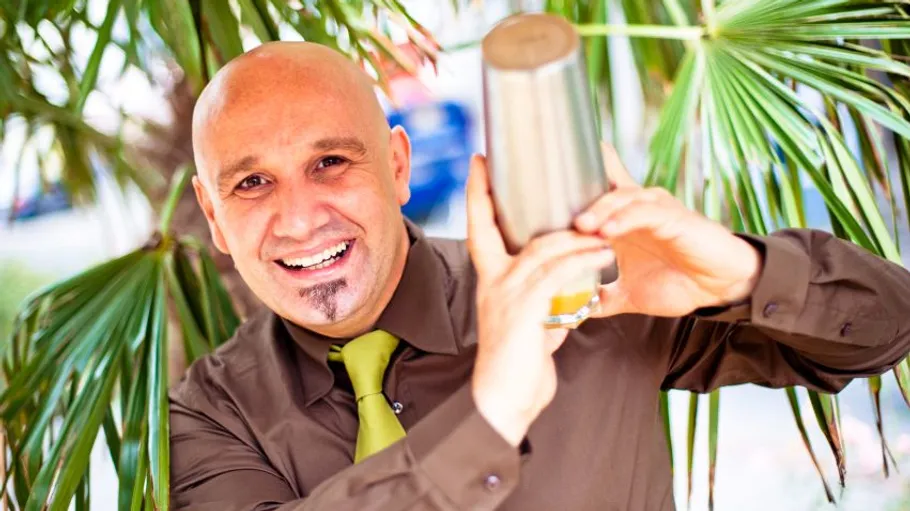 Man shaking cocktail shaker near plants.