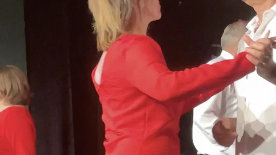 Frau im roten Kleid tanzt auf Bühne.
