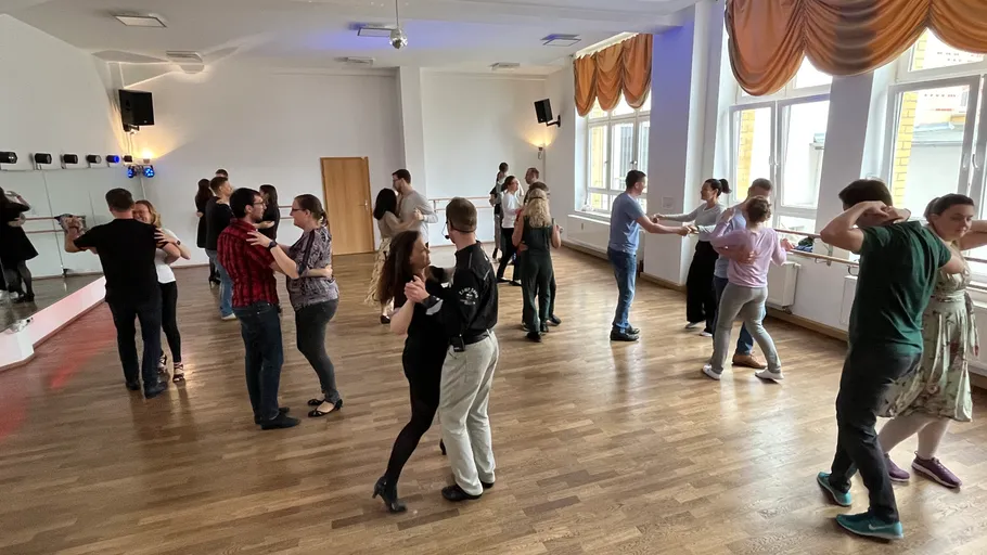 Paare tanzen in einem hellen Tanzstudio.