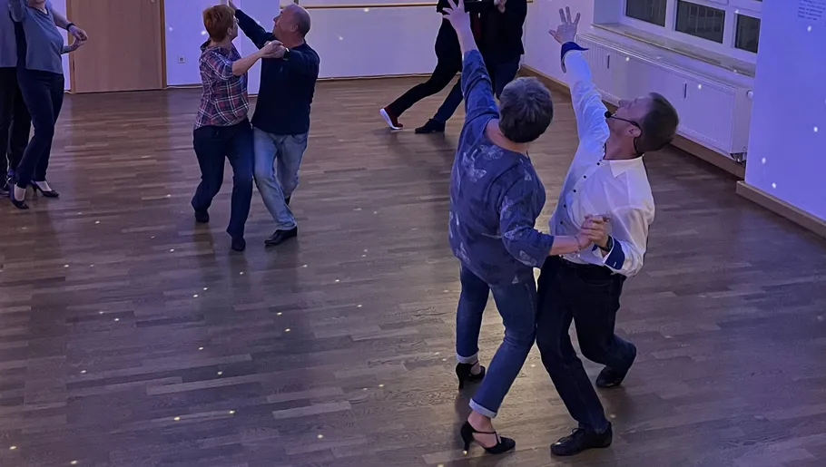 Couples dancing in a dimly lit room.