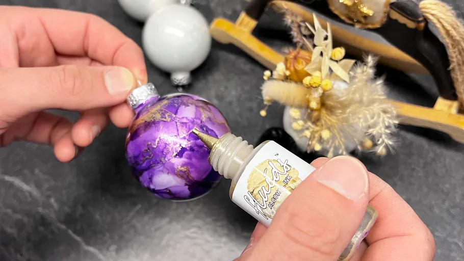 Hand trägt Tinte auf lila Ornament auf.
