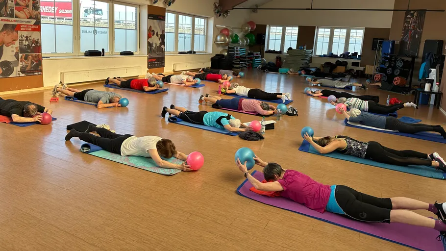 Menschen trainieren mit Bällen im Fitnessstudio.