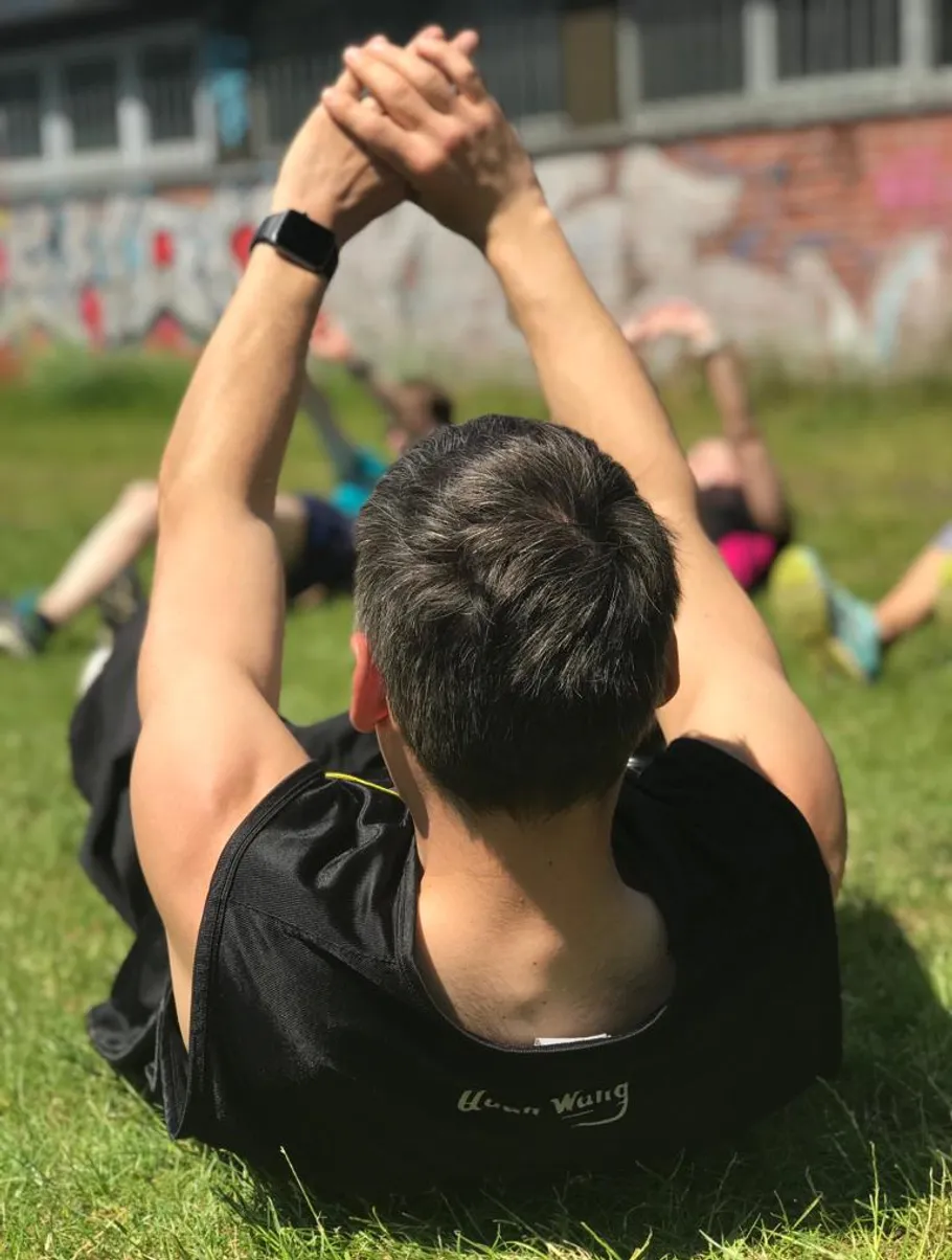 Person macht Outdoor-Übung auf Gras, sonniger Tag.