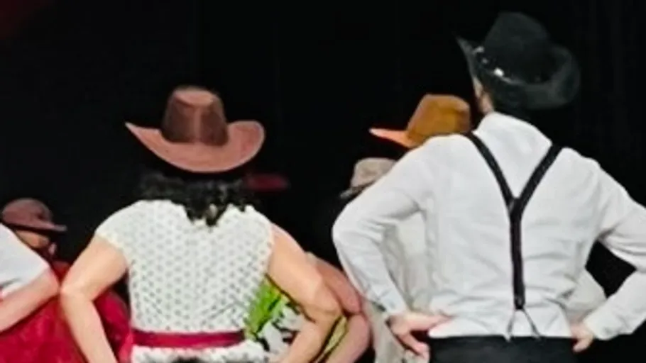 Dancers in cowboy hats performing on stage.