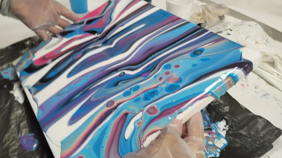 Hands tilting colorful abstract painting canvas.