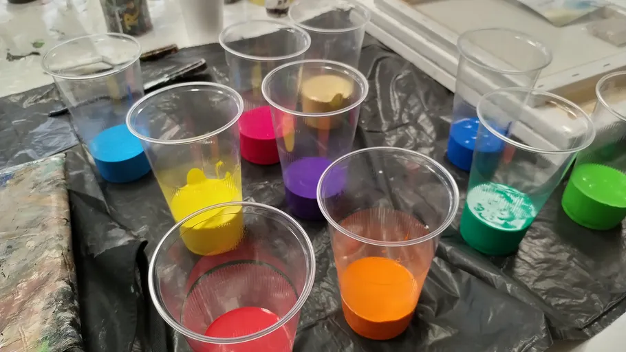Plastikbecher mit bunter Farbe gefüllt.