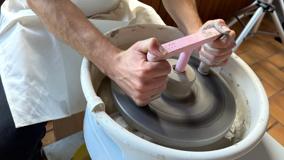 Person using pottery wheel tool indoors.