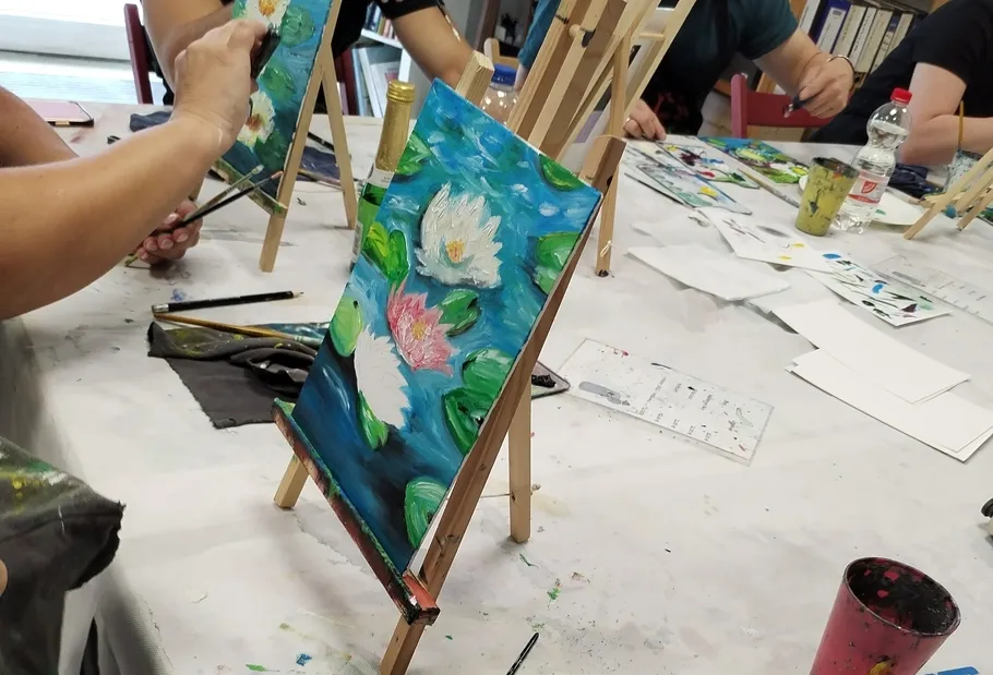 Personen malen auf Staffeleien im Kunstkurs.