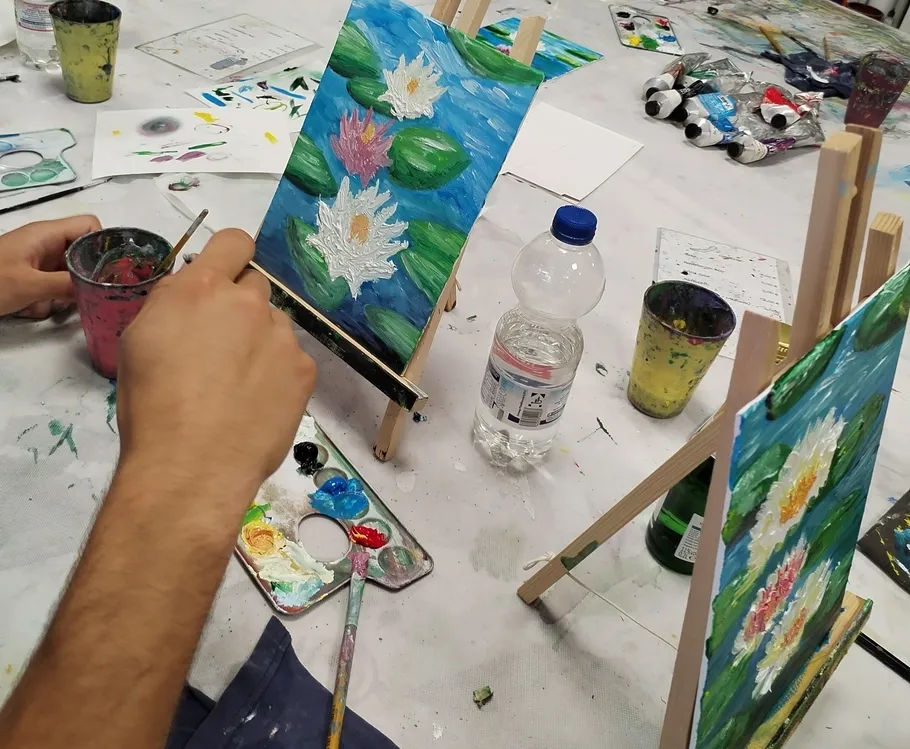 Person painting water lilies in art class.